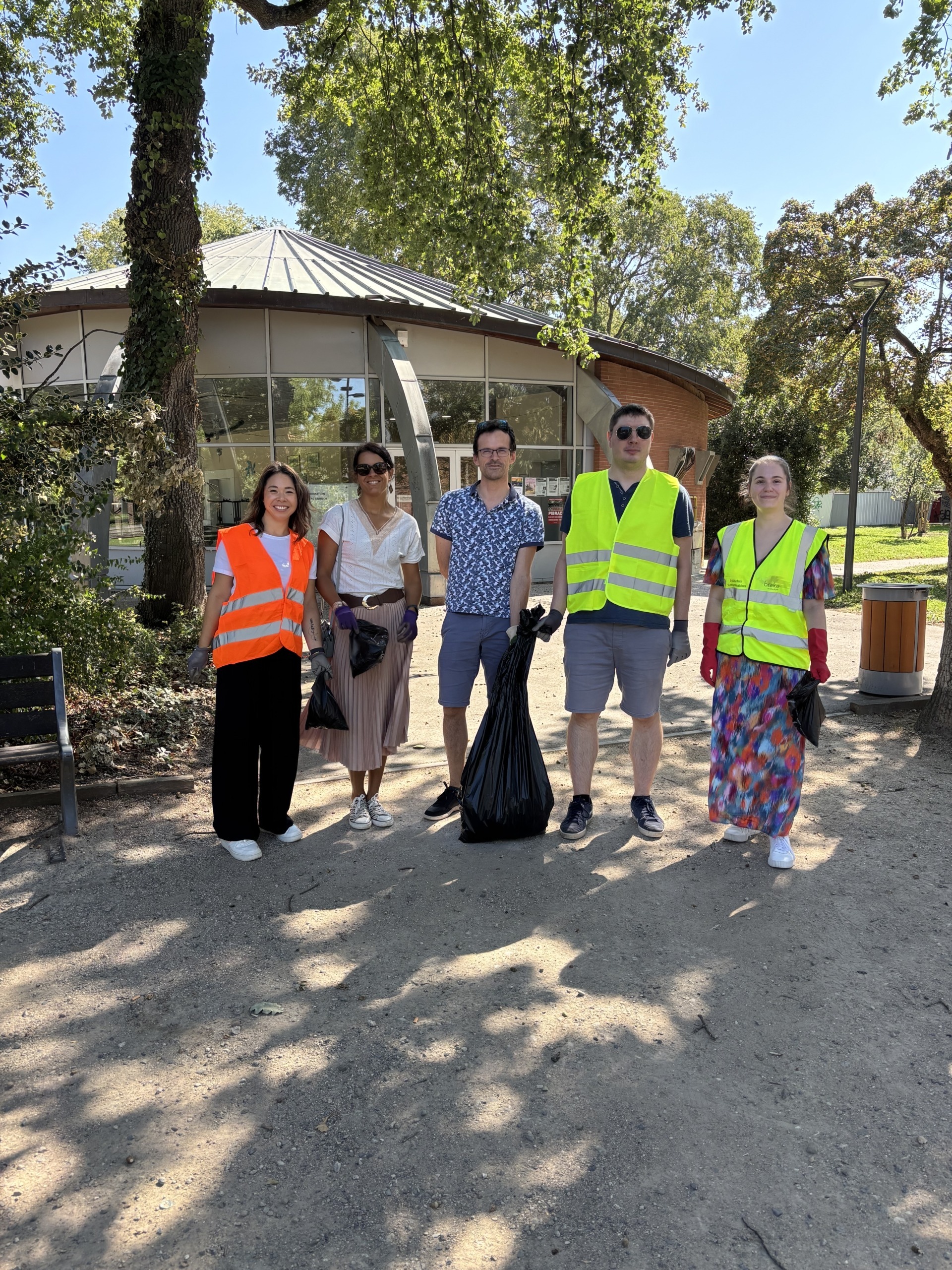 Photo prise de face du groupe de ramassage de Decasoft comprenant 5 personnes, 3 femmes et 2 hommes, portant le sac contenant tous les déchets récupérés.